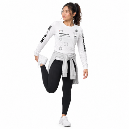 A woman modeling a white long-sleeve athletic top with black graphic prints and text, paired with black leggings and white sneakers, against a plain white background.