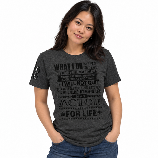 A woman wearing a dark heather gray graphic t-shirt with black text that reads 'WHAT I DO ISN'T EASY, IT'S SAFE. IT'S ME.