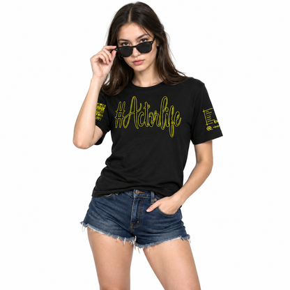 A woman modeling a black short-sleeve graphic T-shirt with yellow text reading '#ActionLife' across the chest, plus yellow graphics on both sleeves, paired with denim shorts against a plain white background.