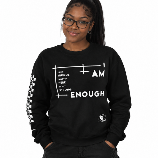 A woman wearing a black crewneck sweatshirt with white graphic text and a checkered sleeve print, set against a plain white background.