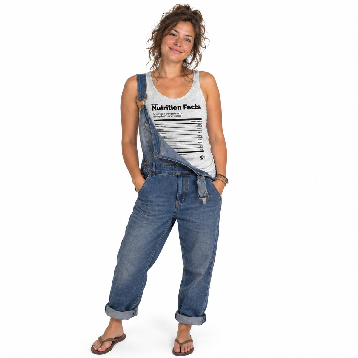 A woman modeling a pair of blue denim overall with a white tank top featuring a 'Nutrition Facts' print, set against a plain white background.
