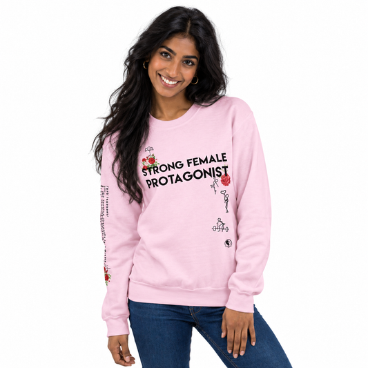 A woman wearing a light pink crewneck sweatshirt with the text 'STRONG FEMALE PROTAGONIST' and small red rose graphics on the front, paired with blue jeans, against a plain white background.