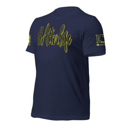 A navy blue short-sleeve t-shirt shown from the back, featuring the text '#Actorlife' printed in a yellow cursive outline across the upper back. The right sleeve (viewer's left) has a small yellow graphic, and the left sleeve (viewer's right) features a small white and yellow measurement-style graphic.